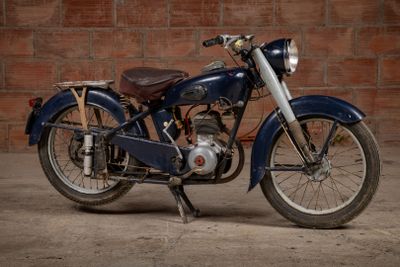 a blue motorcycle that is parked in front of a brick wall