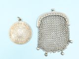 two silver metal purses and a coin on a blue background