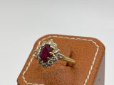une photo d'une bague sertie d'un diamant et d'un rubis, dans un écrin