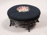 un petit tabouret noir orné d'un motif floral