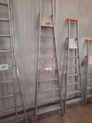 several ladders are lined up against a wall in a warehouse