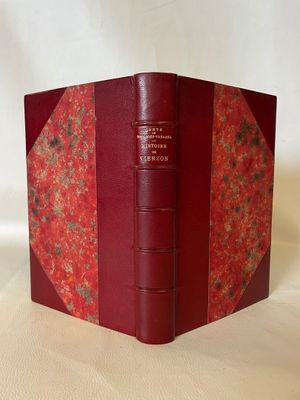 an old book with a red cover sitting on top of a white table