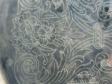 a close up of a silver tray with a design on it