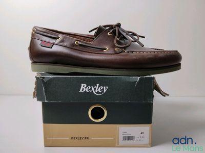 des chaussures bateau marron pour homme posées sur une boîte, sur une surface blanche