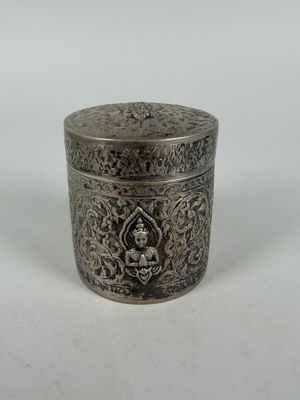 an old silver box with a buddha on it on a white surface