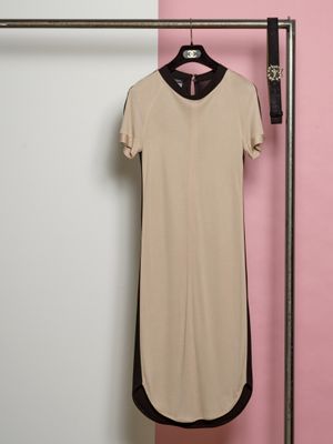 La robe est suspendue à un cintre devant un mur rose.