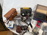 a table that has many items on it including a camera, a camera case, a camera case, a camera case, and other items