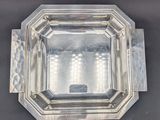 a close up of a silver plate on a black surface