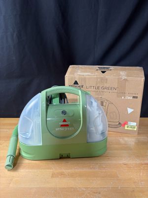 une photo d'un aspirateur vert posé sur une table en bois