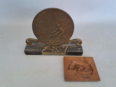 carvings of a man on a bicycle and a horse on a marble base