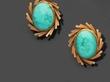 une paire de boucles d'oreilles en turquoise et or sur un fond noir