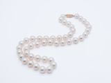 a close up of a white pearl necklace on a white surface