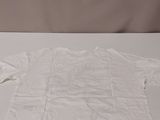a white t - shirt on a white table next to a pair of scissors