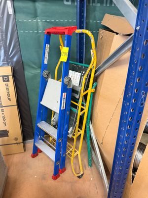 une échelle bleue et jaune à côté d'une pile de cartons