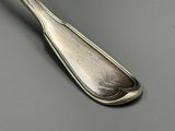 une cuillère en argent posée sur une surface grise avec un fond noir