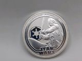 a close up of a silver coin with a star wars logo on it