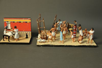 two figurines of people and a building on a table