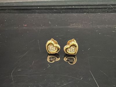 deux boucles d'oreilles en or ornées de diamants, posées sur une surface noire