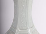 a white vase sitting on a table with a white background