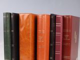 several books are lined up in a row on a white surface