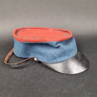 chapeau bleu et rouge muni d'une lanière en cuir, posé sur un fond noir