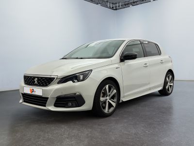 Une voiture blanche est garée dans une grande pièce au sol noir.