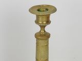 a gold candle holder with a green candle inside of it