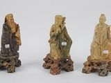 trois figurines chinoises sculptées représentant un homme et une femme, posées sur une souche d'arbre