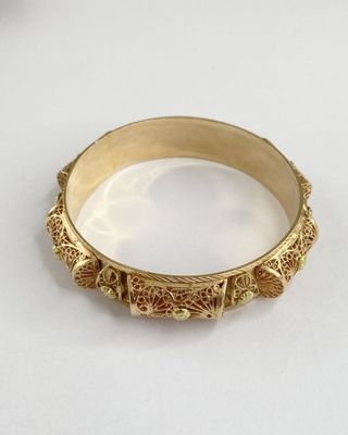 gros plan d'un bracelet en or sur une surface blanche