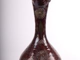 a brown vase that is sitting on a white surface