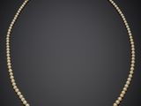 un collier de perles blanches muni d'un fermoir en argent, sur fond noir