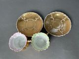 three gold and pink dishes sitting next to each other on a table