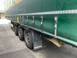 un gros semi-remorque vert garé sur le bord de la route