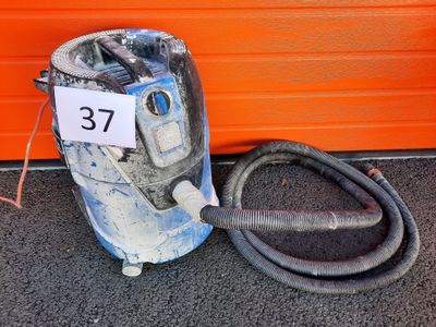 a vacuum that is sitting on the ground next to an orange wall