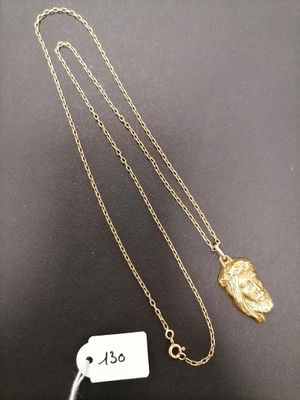 a close up of a gold necklace with a bird on it