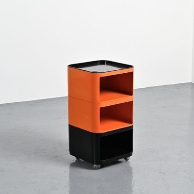 une étagère orange et noire à deux tablettes, montée sur roulettes, dans une pièce