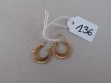 une paire de boucles d'oreilles créoles en or avec une étiquette de prix sur fond blanc