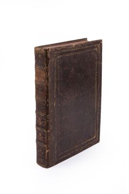 un vieux livre brun posé sur une surface blanche