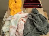 three hats and a scarf sitting on a cardboard box