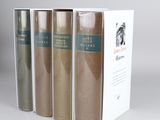 three books in a row on a white surface with a gray background