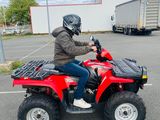 a man riding a red four wheeler atv in a parking lot