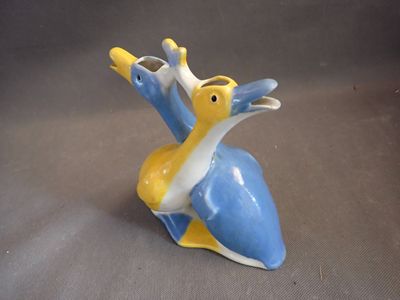 a small blue and yellow bird figurine on a gray surface