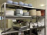 many plates and pans on the shelves in the kitchen