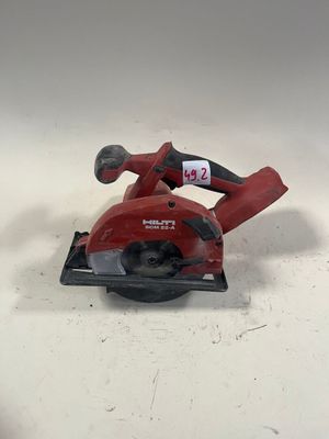 une scie circulaire rouge posée sur une table blanche