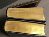 two old books stacked on top of each other on a table