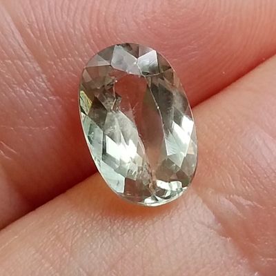 someone is holding a green and white gemstone in their hand