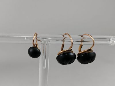a pair of black and gold earrings on a clear stand