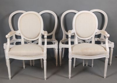 four white painted chairs with white upholstered seats against a gray wall