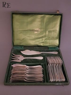 des couverts dans un coffret vert posé sur une table recouverte d'une nappe verte