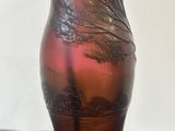a red glass vase with a tree on it on a table